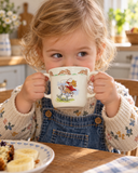 Happy child drinking from Bunnykins double handled mug